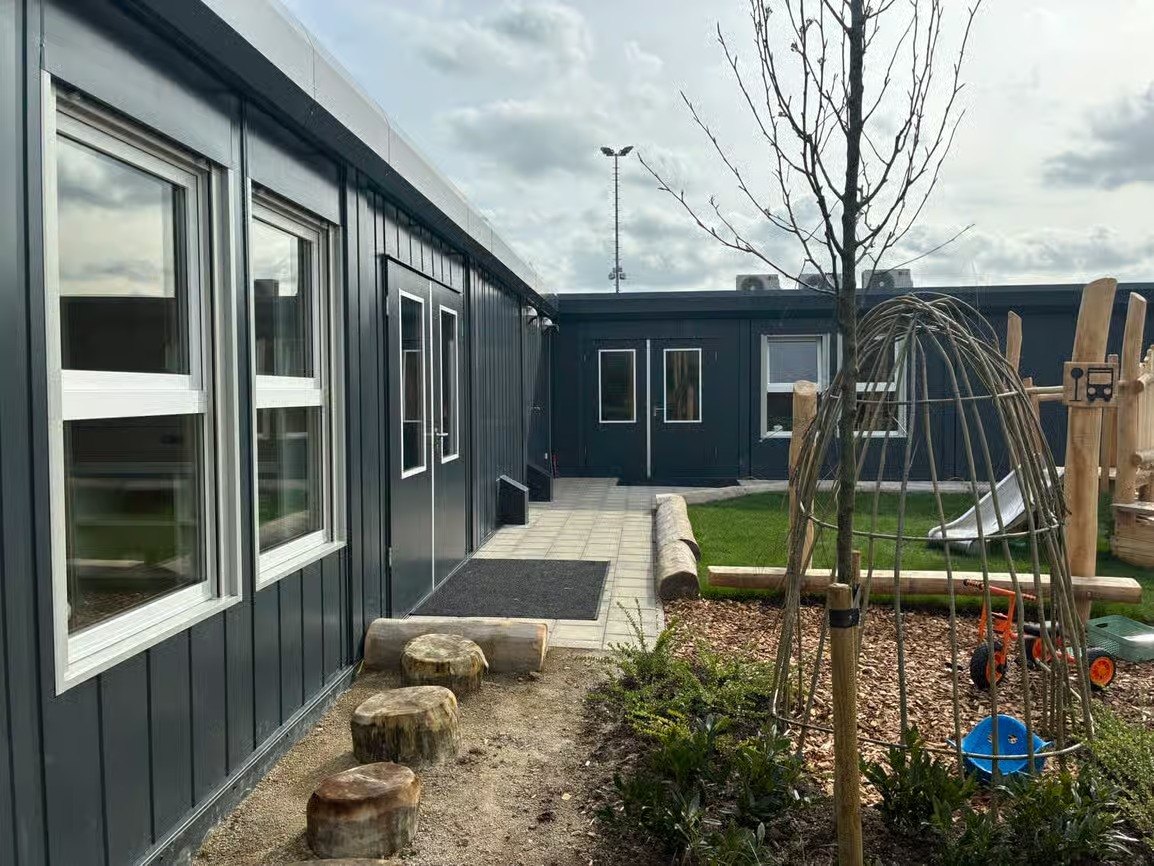 anthracite modular school building beside a natural play area
