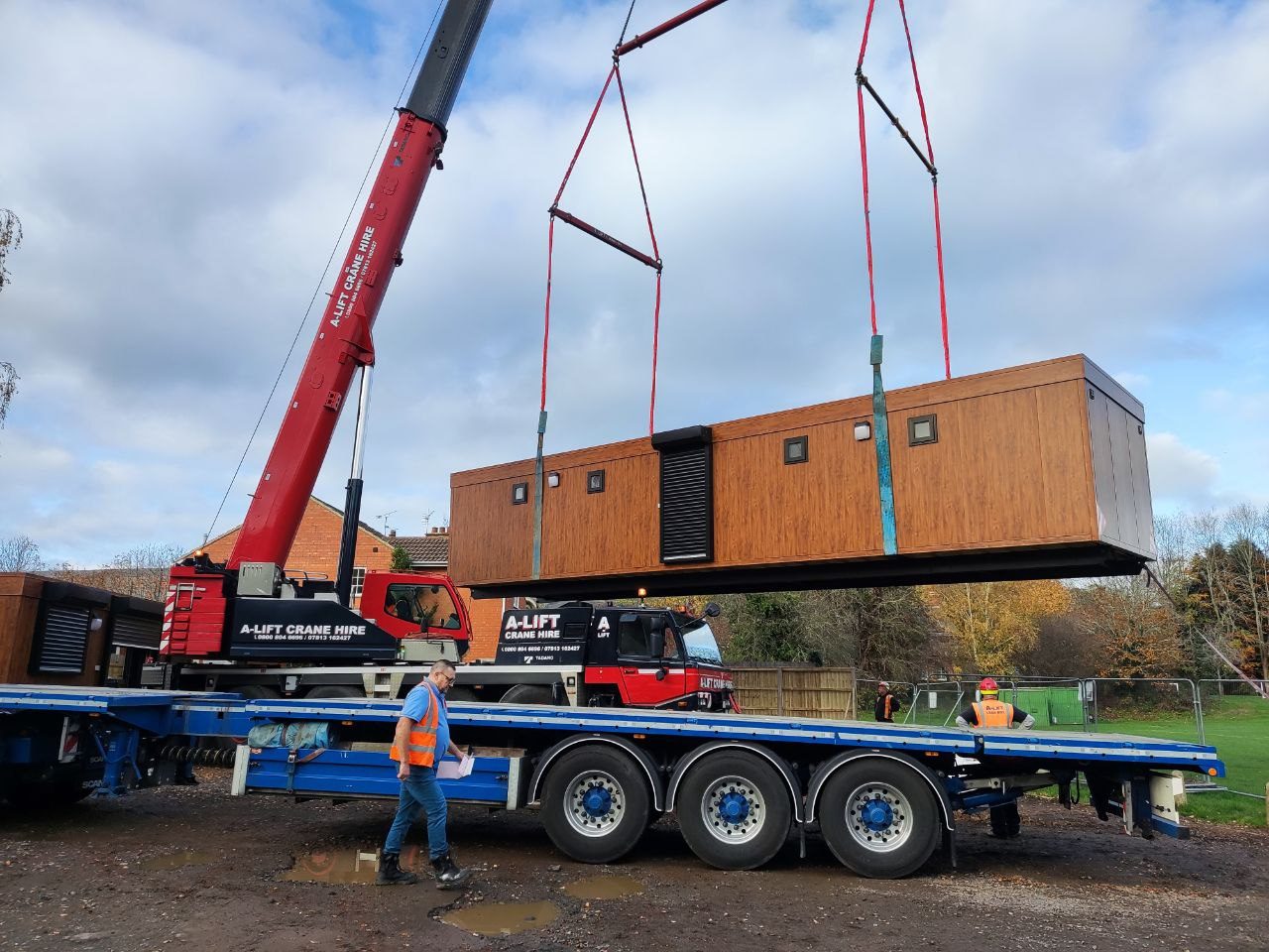 Modular cabin being craned onto a flatbed lorry on site