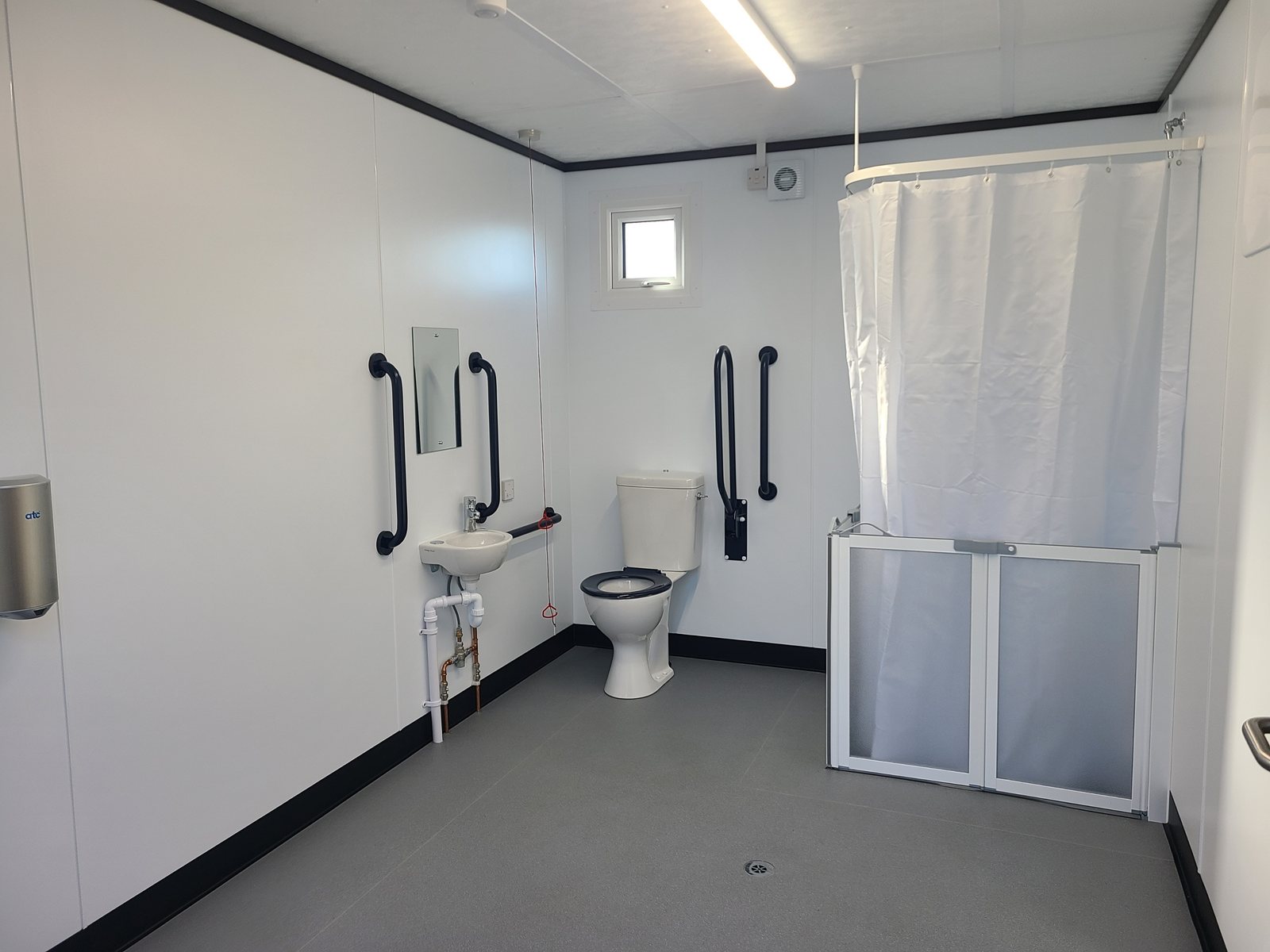 accessible wet room with grab rails, shower curtain and baby change unit