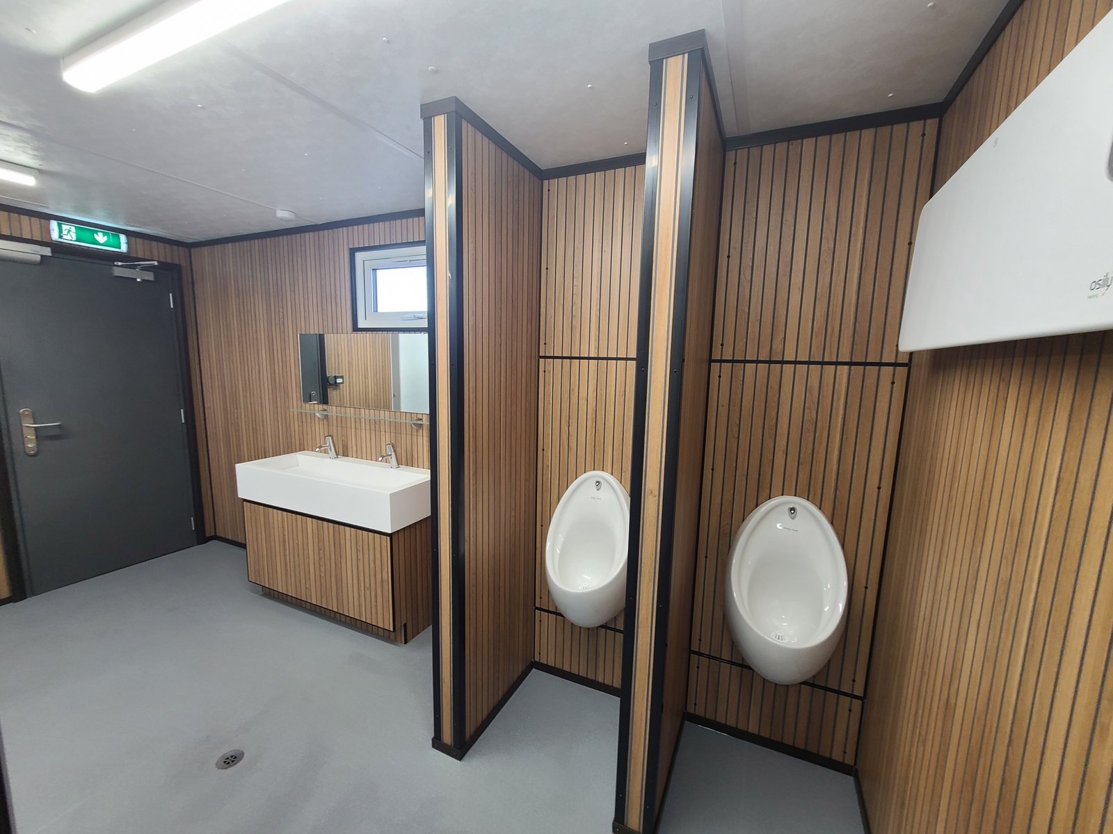 gents washroom in a luxury campsite toilet block with wood slat panelling and urinal bays