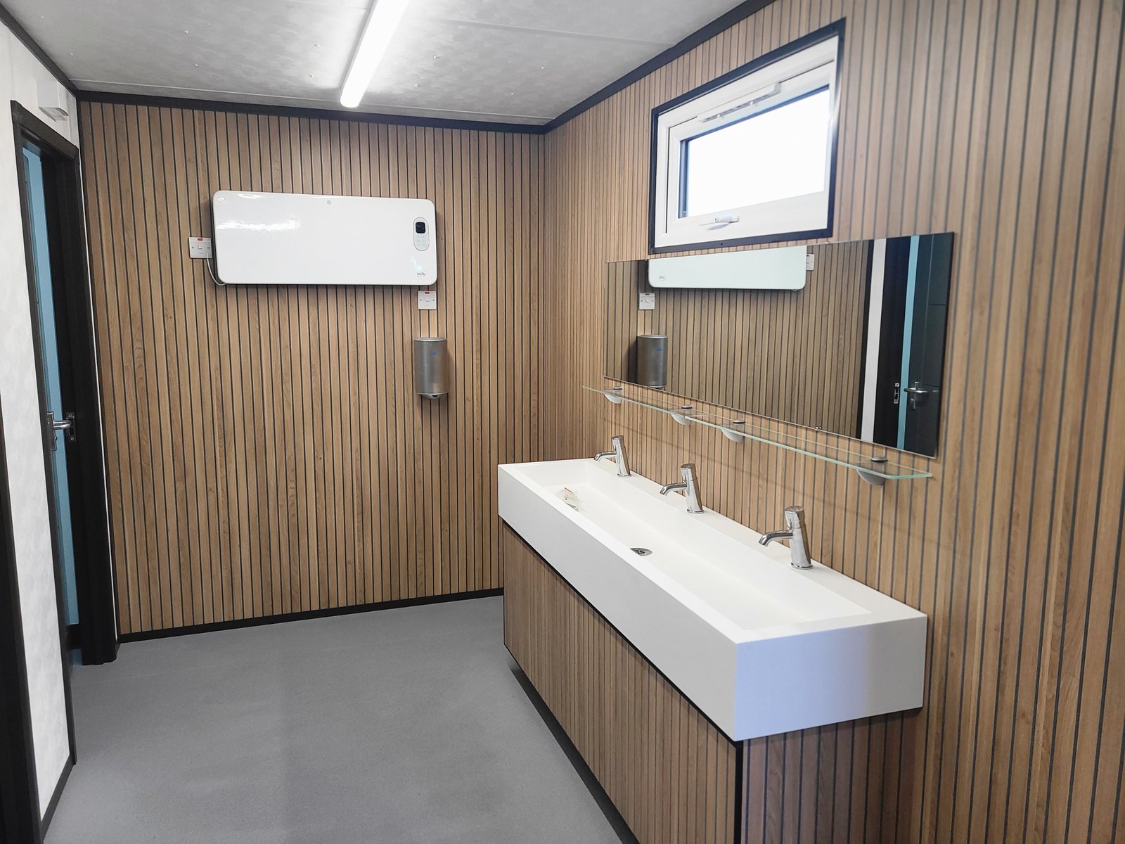 trough basin and mirror against wood slat panelling inside a luxury washroom block