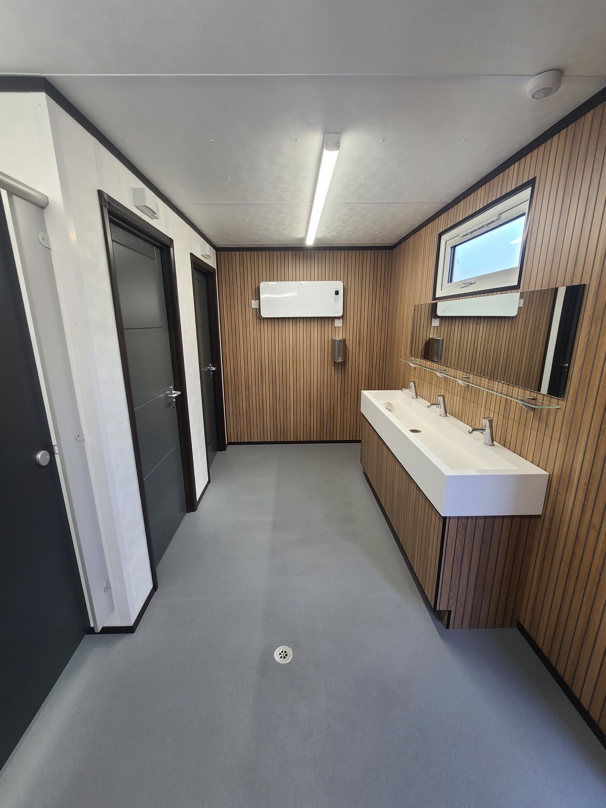 washroom corridor with trough basin and shower cubicles