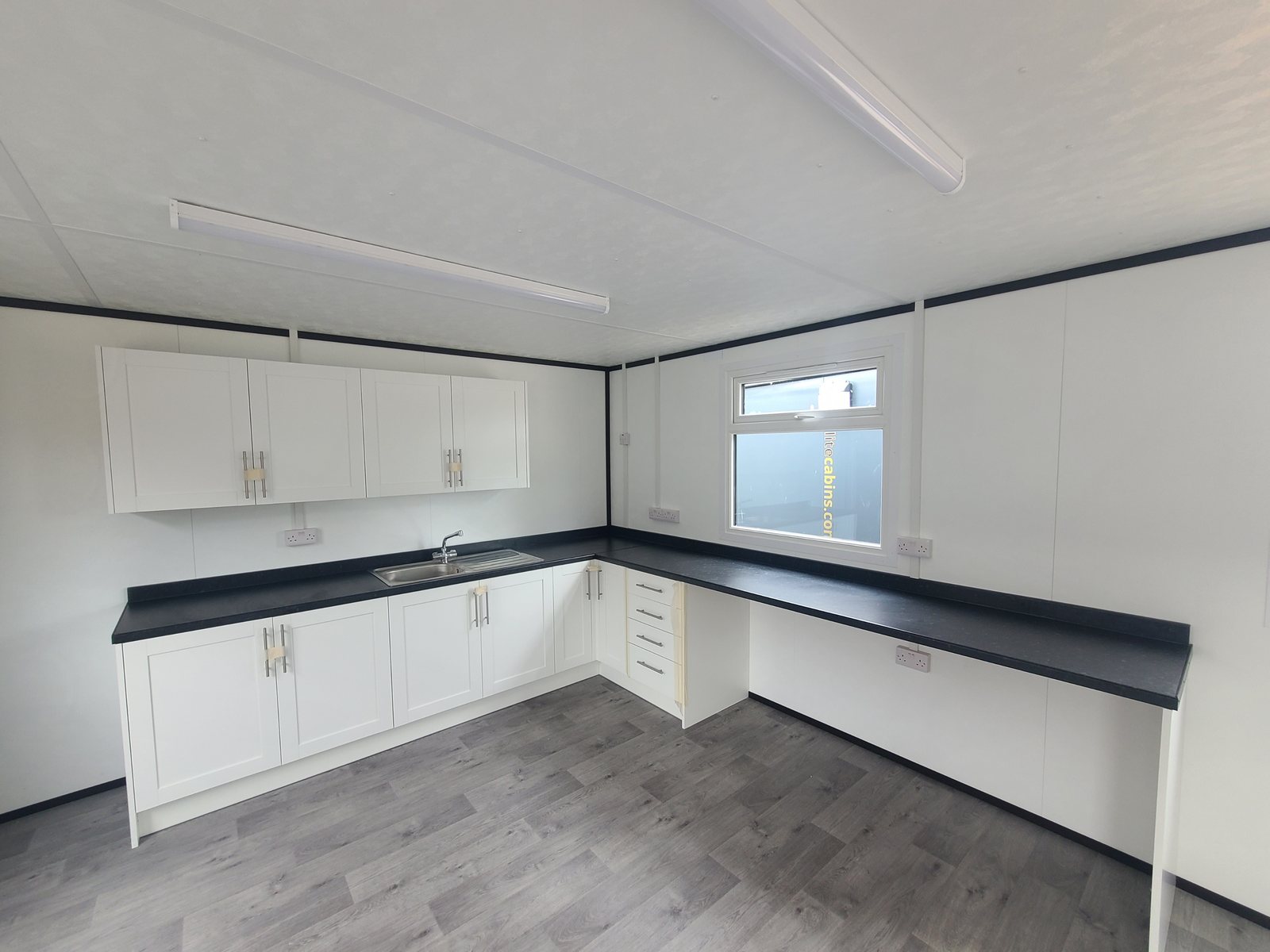 staff canteen kitchen run with white units and dark worktop
